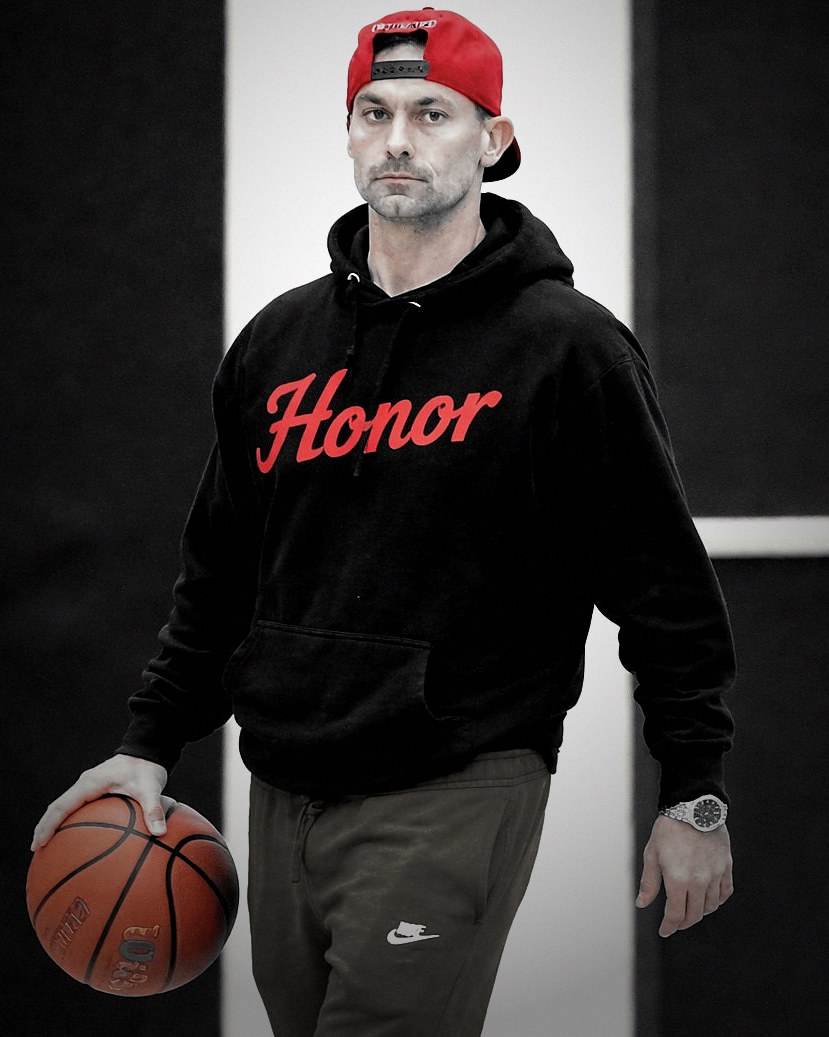Coach Shaun Gerardo on a basketball court, dribbling a ball, wearing a black Honor hoodie